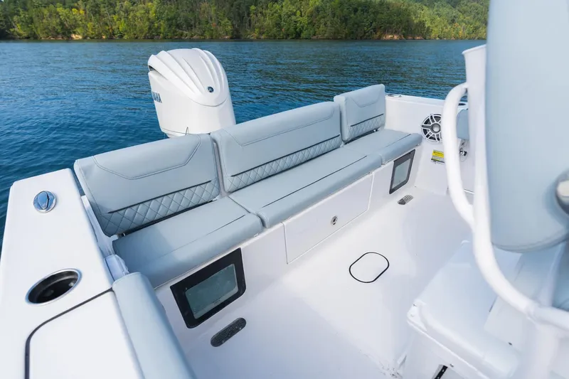 Slide: The Image of 2026 Sportsman Heritage 231 Center Console boat interior with cushioned seating on a serene lake. - 10