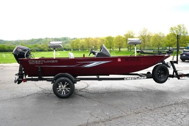 Slide: The Image of 2024 Crestliner 1600 Storm boat on trailer, parked outdoors with scenic background. - 4
