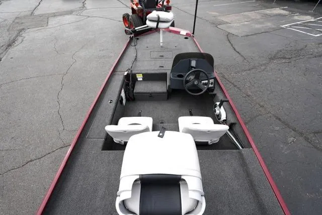 Slide: The Image of 2024 Crestliner 1600 Storm boat interior with seating and steering wheel, parked on pavement. - 8