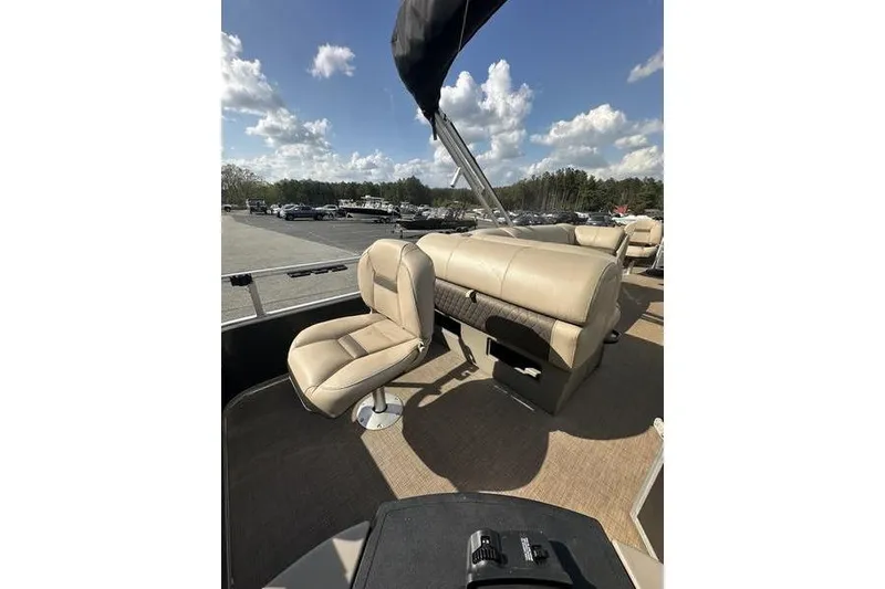 The Image of 2023 Sun Tracker Fishin' Barge 21 interior with beige seating under a sunny sky. - 1