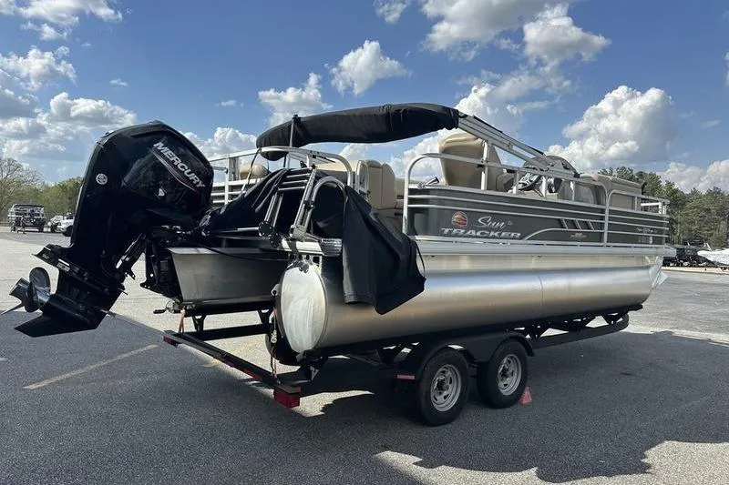 Slide: The Image of 2023 Sun Tracker Fishin' Barge 21 pontoon boat on trailer under blue sky. - 10