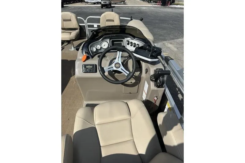 Slide: The Image of 2023 Sun Tracker Fishin' Barge 21 boat interior with steering wheel and beige seating. - 11