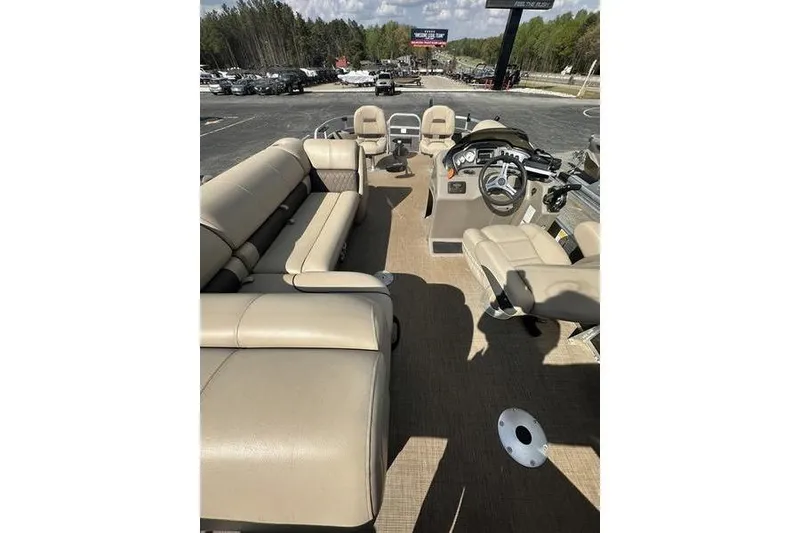 Slide: The Image of 2023 Sun Tracker Fishin' Barge 21 interior with beige seating and steering console. - 4