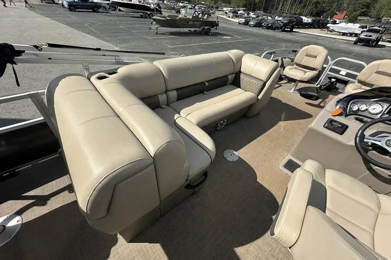 Slide: The Image of 2023 Sun Tracker Fishin' Barge 21 interior with beige seating and steering console. - 5