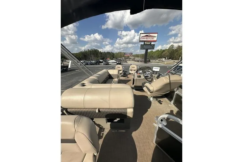 Slide: The Image of 2023 Sun Tracker Fishin' Barge 21 interior with beige seating under a blue sky. - 6