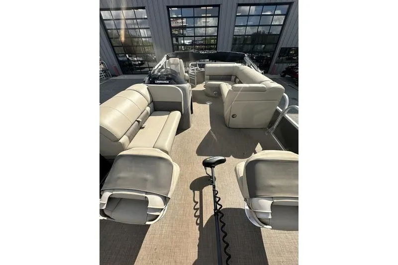 Slide: The Image of 2023 Sun Tracker Fishin' Barge 21 interior with beige seating and fishing equipment. - 7