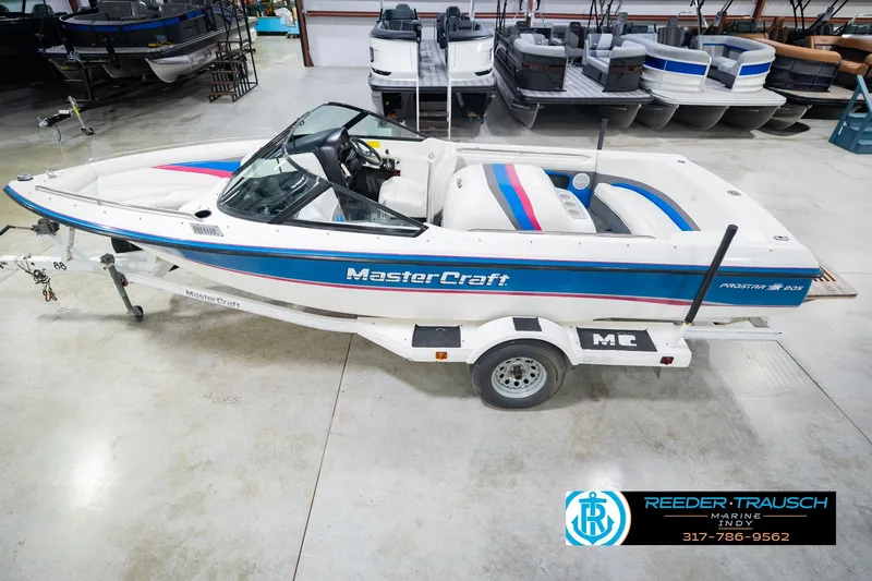The Image of 1992 MasterCraft ProStar boat on trailer in showroom, featuring blue and pink accents. - 0