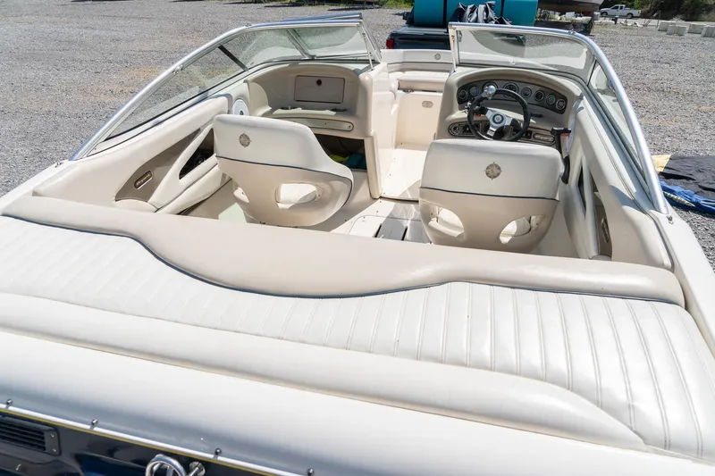 Slide: The Image of 2007 Bryant 190 boat interior with beige seating and dashboard, parked outdoors. - 10
