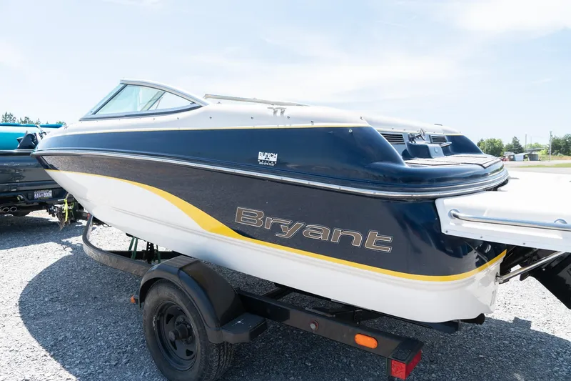 Slide: The Image of 2007 Bryant 190 boat on trailer, blue and white with yellow accents, parked outdoors. - 6