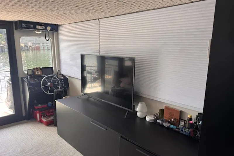 Slide: The Image of Interior of a 1985 Three Buoys houseboat with steering wheel and TV setup. - 11