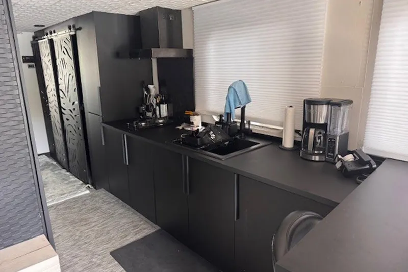 Slide: The Image of Modern kitchen interior on a 1985 Three Buoys houseboat, featuring sleek black cabinetry and appliances. - 15