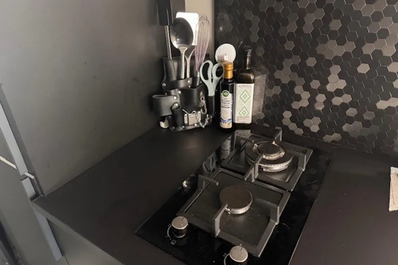 Slide: The Image of Modern kitchen in 1985 Three Buoys houseboat with black hexagonal backsplash and gas stove. - 16