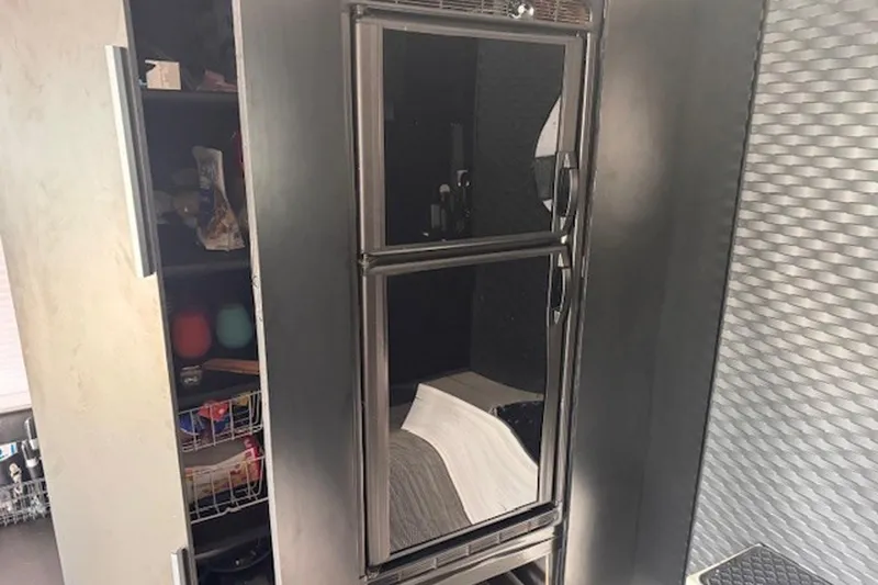 Slide: The Image of Interior of a 1985 Three Buoys houseboat featuring a compact refrigerator and storage shelves. - 17