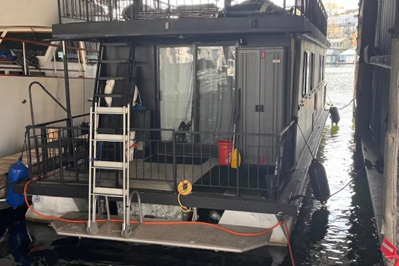 Slide: The Image of 1985 Three Buoys houseboat docked, featuring a ladder and safety equipment. - 3