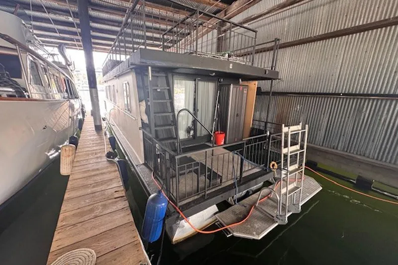 Slide: The Image of 1985 Three Buoys houseboat docked in a covered marina, featuring a rooftop deck. - 4