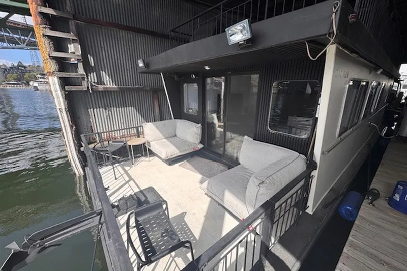 Slide: The Image of 1985 Three Buoys houseboat with outdoor seating on a sunny dockside. - 9