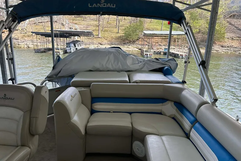 Slide: The Image of 2008 Landau Atlantis 250 Sport Cruise pontoon boat with beige and blue seating on a lake. - 18
