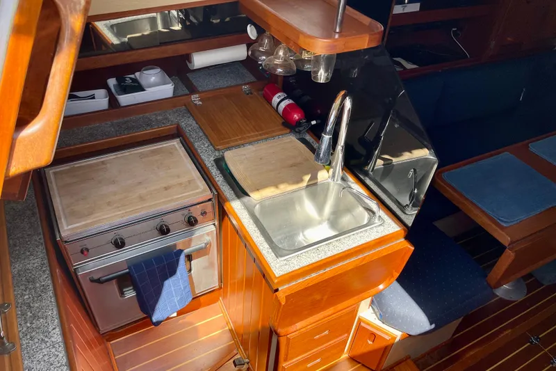Slide: The Image of Interior of a 1979 Catalina 38 sailboat kitchen with stove, sink, and wooden cabinetry. - 27