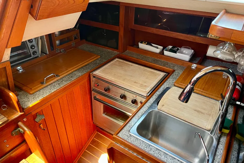 Slide: The Image of 1979 Catalina 38 yacht kitchen with wooden cabinetry, stove, and stainless steel sink. - 29