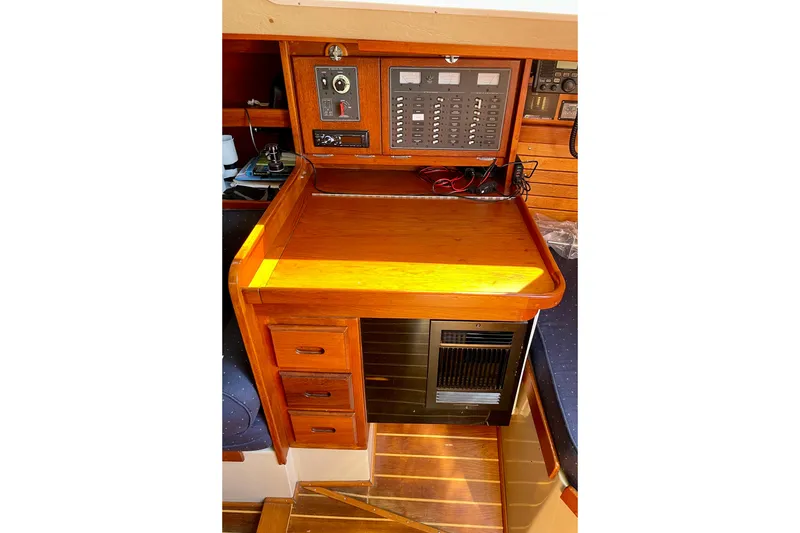 Slide: The Image of Navigation station of a 1979 Catalina 38 sailboat with control panel and wooden cabinetry. - 38
