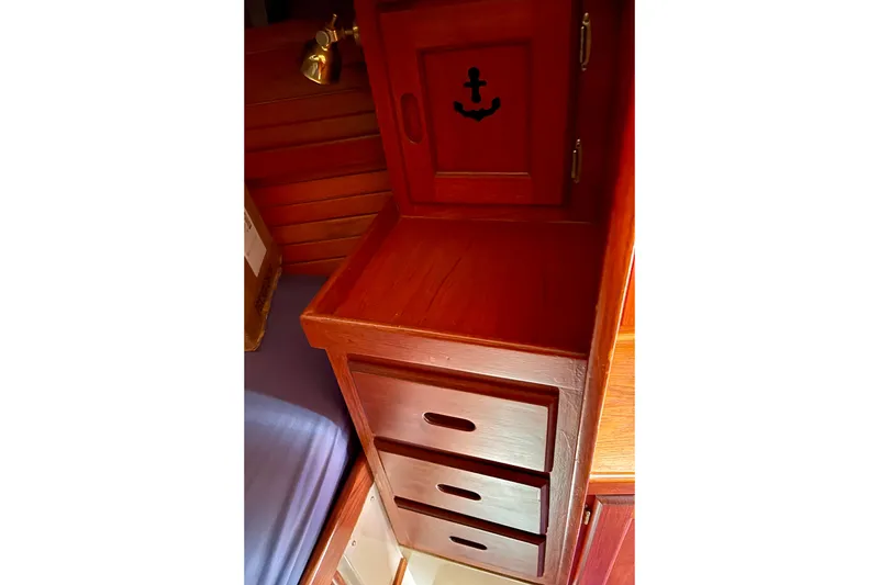 Slide: The Image of Wooden cabinetry inside a 1979 Catalina 38 sailboat, featuring drawers and an anchor design. - 45