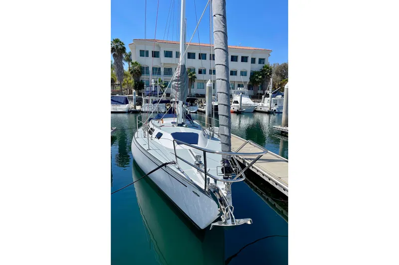 Slide: The Image of 1979 Catalina 38 sailboat docked in a marina, with a building in the background. - 5