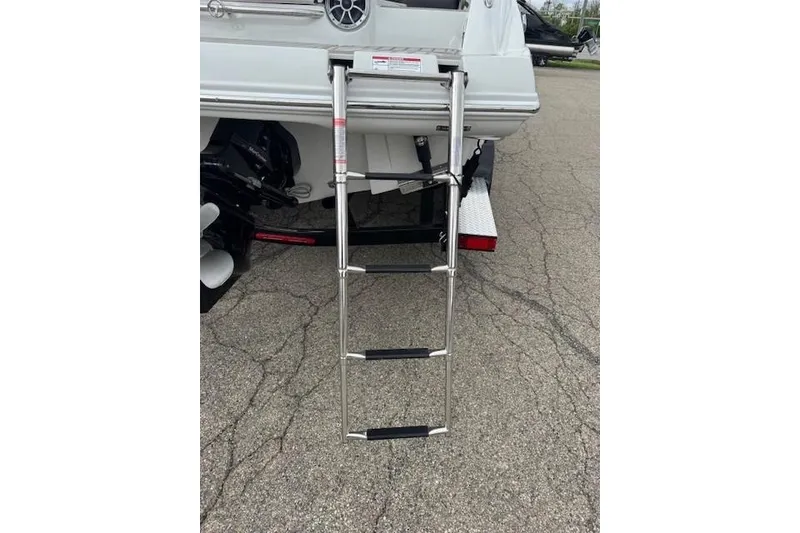 Slide: The Image of 2025 Crownline 280 SS boat with extended swim ladder on pavement. - 18