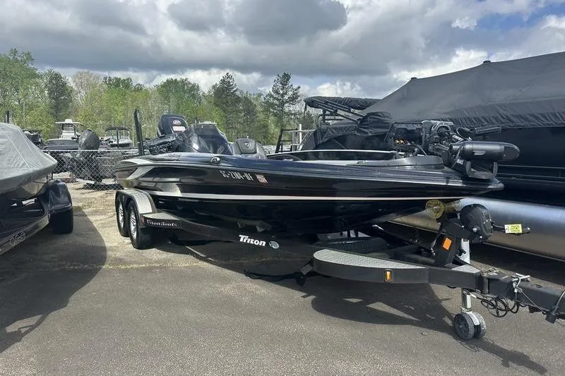 Slide: The Image of 2016 Triton 20 TrX boat parked outdoors under cloudy sky. - 2