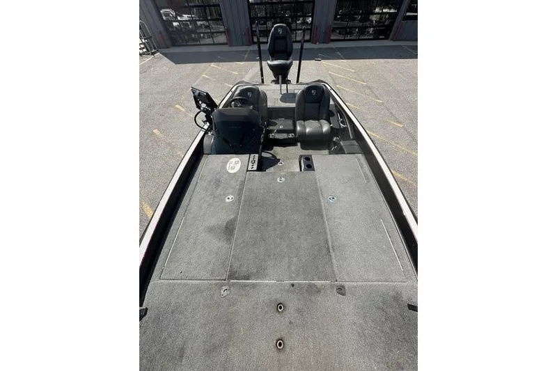 Slide: The Image of 2016 Triton 20 TrX boat interior with seating and control panel, parked outdoors. - 9
