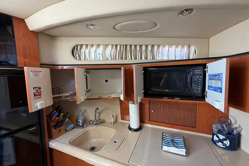 Slide: The Image of 2001 Sea Ray 410 Express Cruiser kitchen with sink, microwave, and storage cabinets. - 17