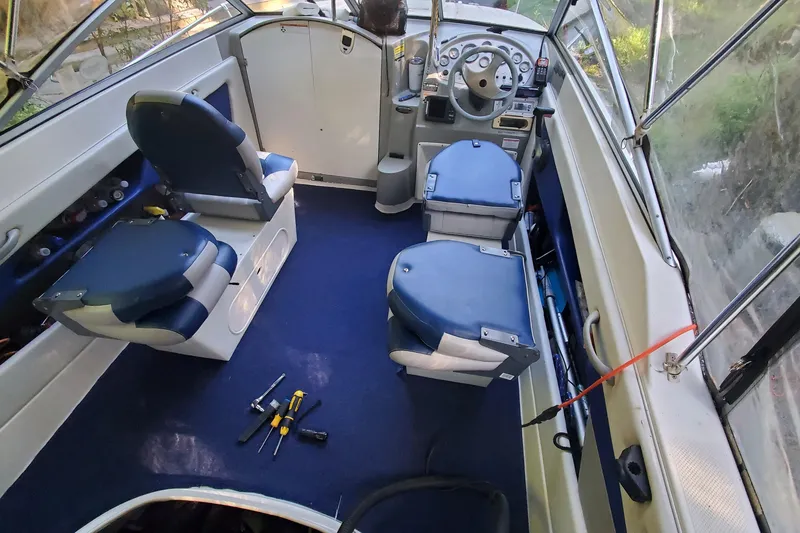 Slide: The Image of Interior of a 2006 Bayliner 192 Discovery Cuddy boat with blue seating and tools. - 3