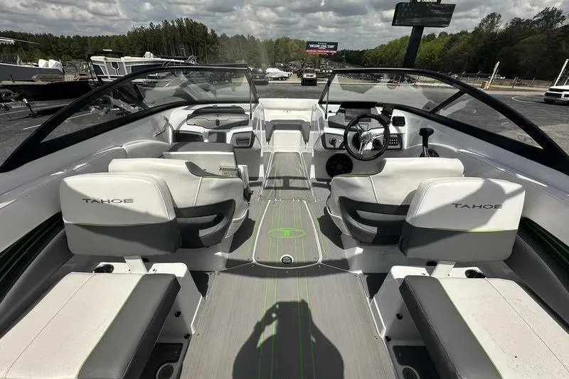 Slide: The Image of 2024 Tahoe 210 S boat interior with modern seating and steering, parked outdoors. - 10