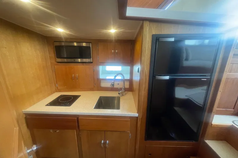 Slide: The Image of 1968 Hatteras 34 Sport Fisherman kitchen with sink, stove, microwave, and fridge. - 25