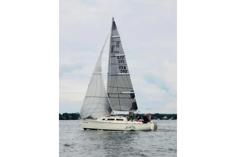 The Image of 1984 S2 7.9 Grand Slam sailboat on calm water with crew onboard. - 1