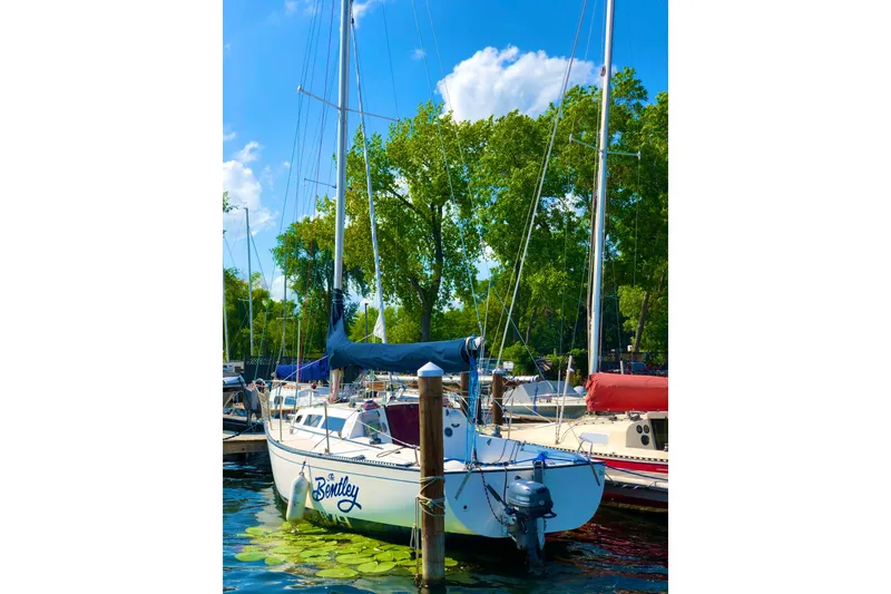 Slide: The Image of 1984 S2 7.9 Grand Slam sailboat docked, surrounded by lush greenery and clear blue sky. - 5