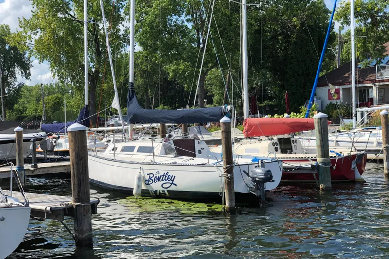 Slide: The Image of 1984 S2 7.9 Grand Slam sailboat docked at marina with lush greenery. - 6