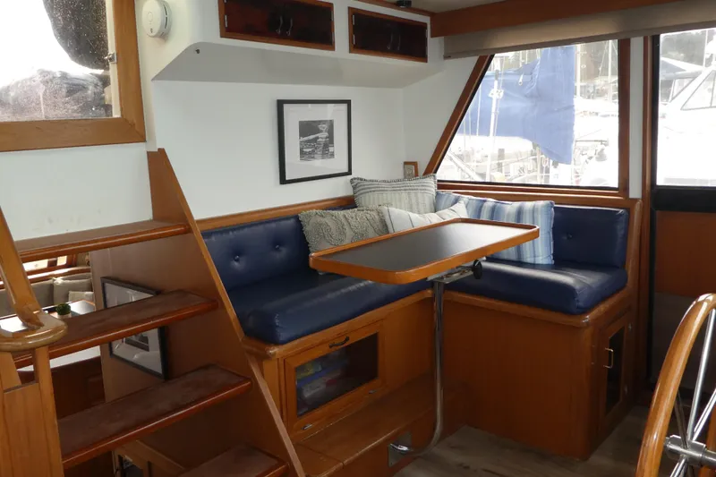 Slide: The Image of 1989 Angel Pilothouse interior with blue cushioned seating, wooden table, and nautical decor. - 12
