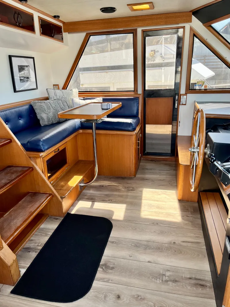 Slide: The Image of 1989 Angel Pilothouse interior with dining area, wooden stairs, and steering wheel. - 13