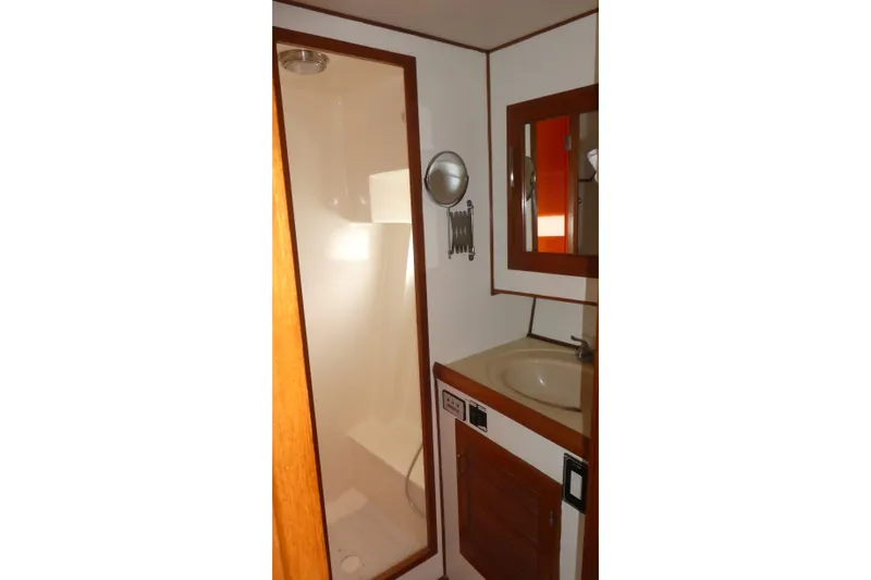 Slide: The Image of 1989 Angel Pilothouse bathroom with shower, sink, and mirror in wooden finish. - 29