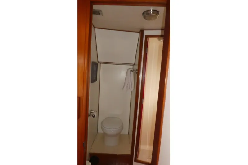 Slide: The Image of 1989 Angel Pilothouse bathroom with toilet and shower, featuring wooden door and towel rack. - 31