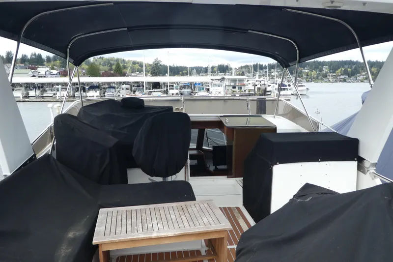 Slide: The Image of 1989 Angel Pilothouse yacht deck with covered seating, wooden table, and marina view. - 32