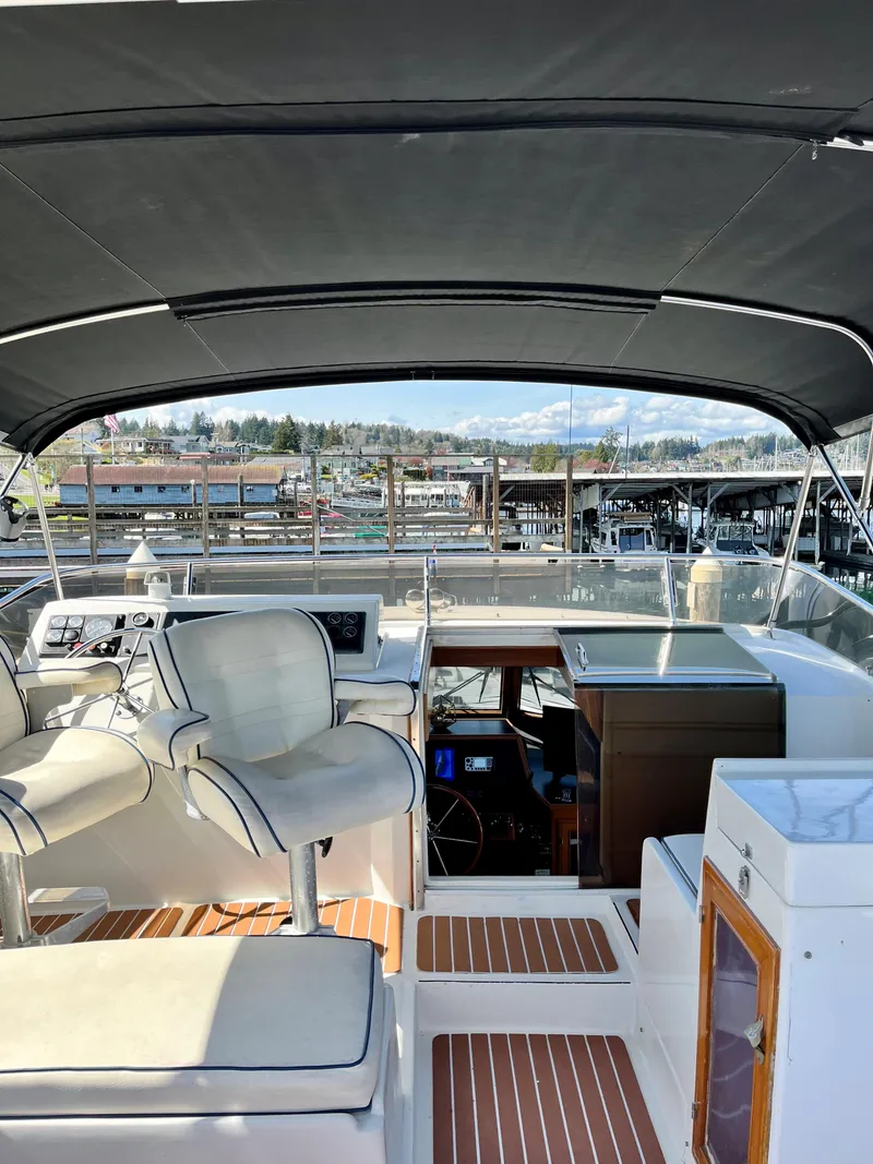 Slide: The Image of 1989 Angel Pilothouse boat interior with helm, seating, and marina view. - 44