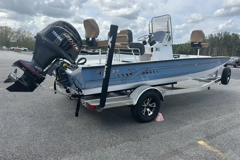 The Image of 2025 Xpress H20B Bay boat with Yamaha engine on trailer, parked outdoors. - 1