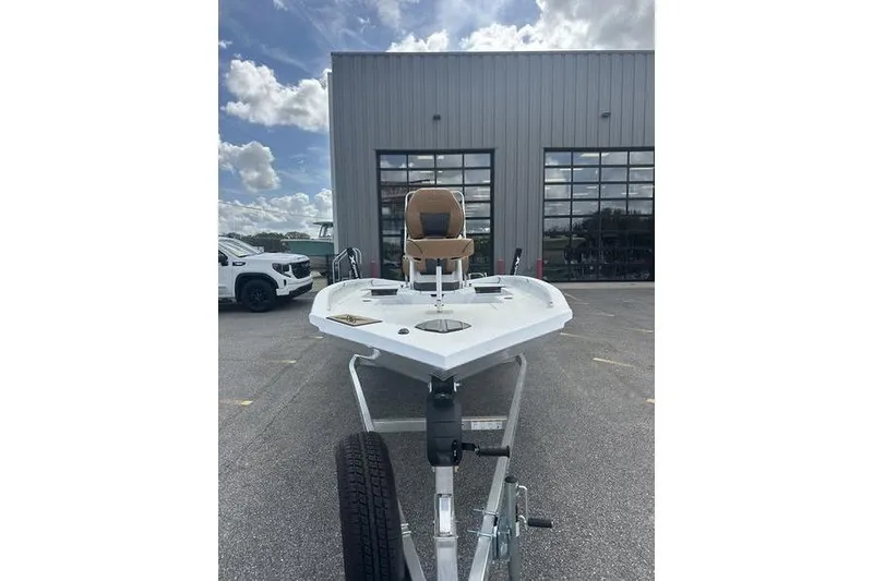 Slide: The Image of 2025 Xpress H20B Bay boat on trailer, parked outside a building under a cloudy sky. - 14