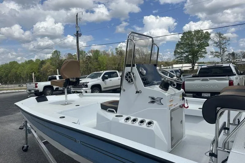 Slide: The Image of 2025 Xpress H20B Bay boat with center console, parked outdoors under a cloudy sky. - 15