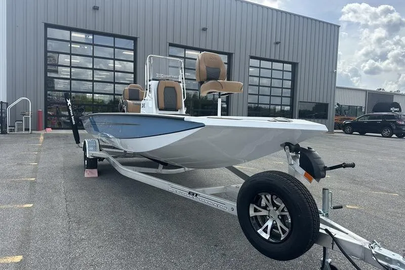Slide: The Image of 2025 Xpress H20B Bay boat on trailer outside a modern building. - 16
