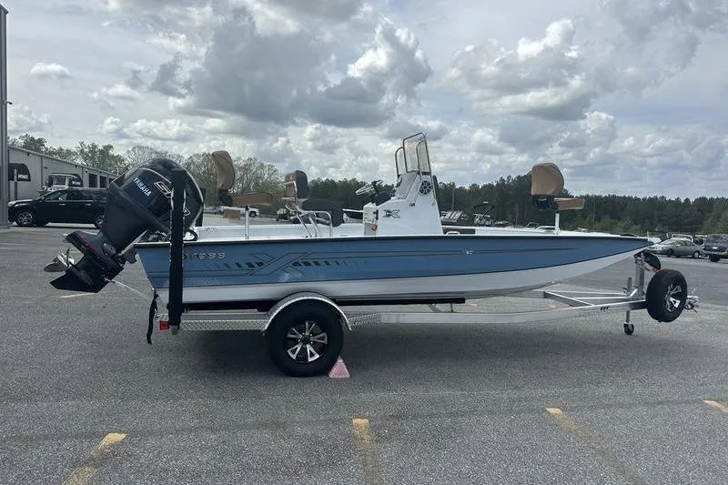 Slide: The Image of 2025 Xpress H20B Bay boat on trailer, parked outdoors under cloudy sky. - 17