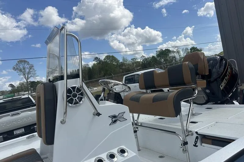 Slide: The Image of 2025 Xpress H20B Bay boat interior with seating and steering, under a partly cloudy sky. - 9