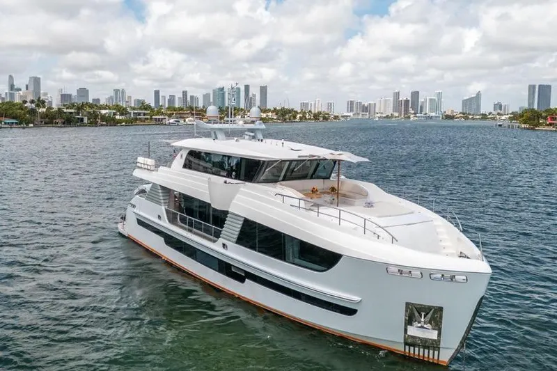 The Image of Luxurious 2020 Hargrave C92 yacht cruising near a city skyline under a partly cloudy sky. - 1