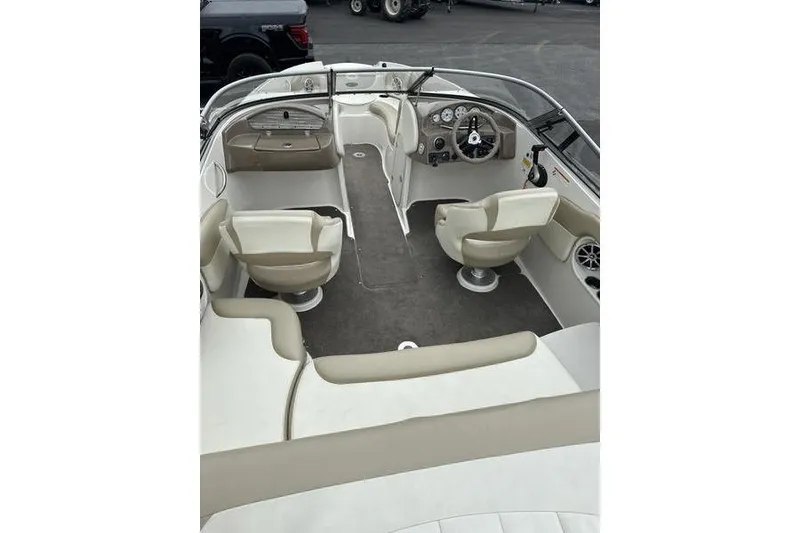 Slide: The Image of 2015 Stingray 208 LR boat interior with beige seating and steering console. - 12